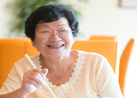 Happy 60s Senior Asian Woman dining indoors