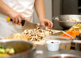 Chef cutting the mushrooms on a wooden board