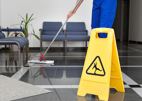 Close-up Of Man Cleaning The Floor With Yellow Wet Floor Sign