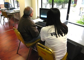 a volunteer helping with a senior on how to uses a computer