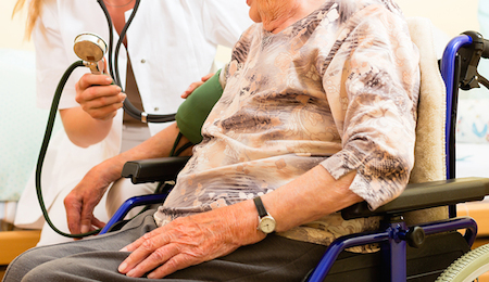 Young nurse and female senior in nursing home, the blood pressure is going to be measured