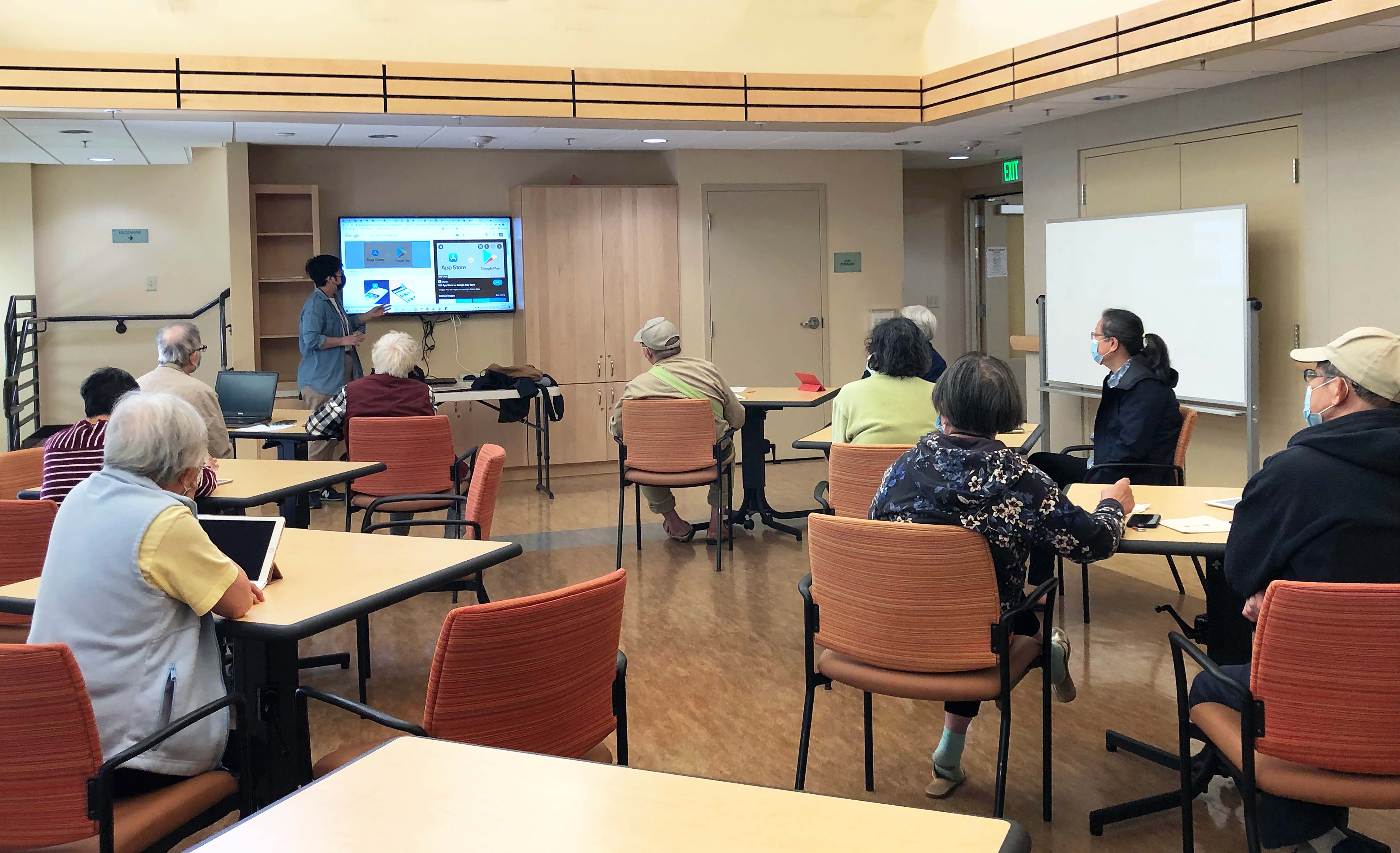 a volunteer helping with a senior on how to uses a computer